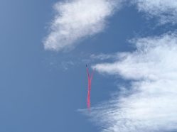 Dynamický záběr na dva letouny Red Arrows (tzv. Synchro Pair) při manévru, kdy se proti sobě řítí a zanechávají kouřovou stopu.
